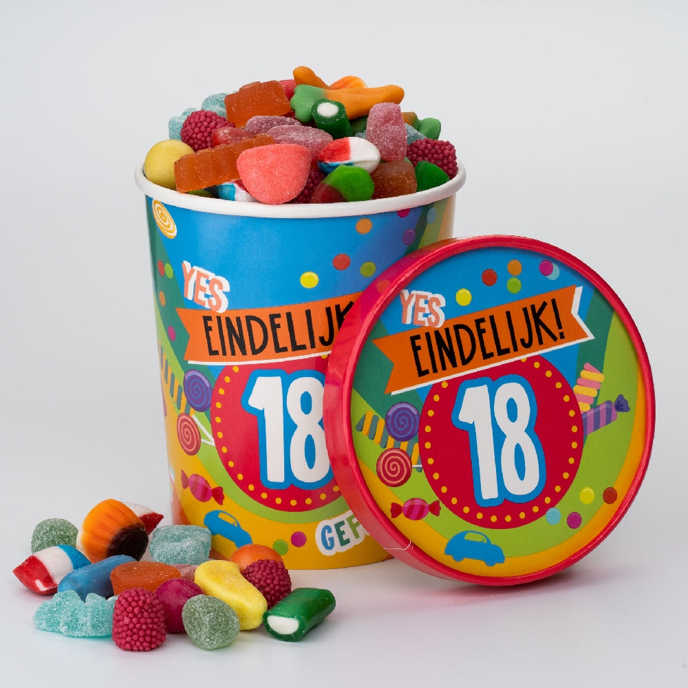  Candy Bucket 18 jaar gevuld met kleurrijke snoepjes, met het rode deksel ernaast.