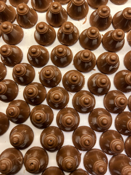 Kerstklokjes van melkchocolade met luchtige slagroomvulling, ambachtelijk gemaakt voor de feestdagen
